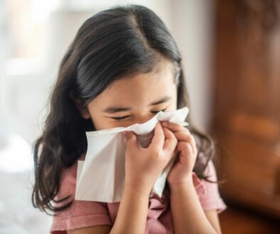 A young girl blowing her nose in a tissue bloody boogers