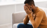 An African American Man With His Hands Covering His Face Dealing with Stress Can Stress Cause Epileptic Seizures