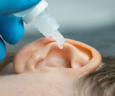 Closeup of a Doctor Wearing Blue Gloves Dripping Ear Drops Into a Patient’s Ear Can Earwax Cause Tinnitus