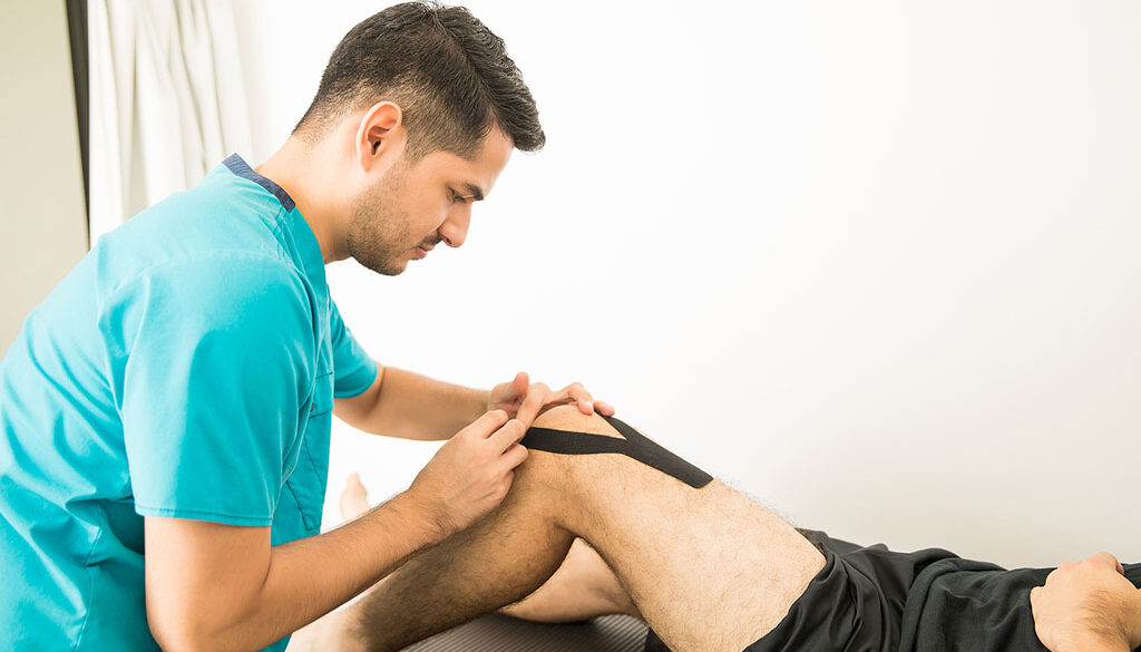 An Orthopedics Sports Medicine Doctor Applying KT Tape to an Athlete’s Knee Laying on a Table